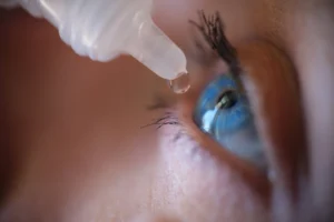 imagem de uma mulher pingando lagrima artificial no olho