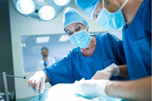 dois médicos uniformizados realizando cirurgia de vitrectomia em paciente