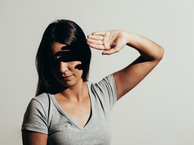 Mulher cobrindo os olhos com a mão por dificuldade de olhar para a luz: o que é fotofobia
